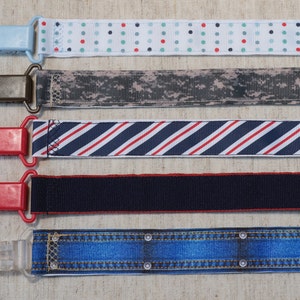 May include: Five different fabric ribbon clips with various patterns. The clips are made of plastic and have a spring-loaded mechanism. The ribbons are in various colors and patterns, including blue, red, white, and black.