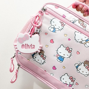 May include: Pink Hello Kitty lunch bag with a zipper closure and a Hello Kitty name tag that says "Olivia".