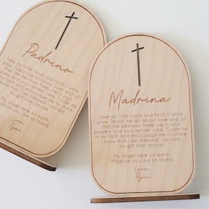 May include: Two wooden plaques with a cross design and a message for a Padrino and Madrina. The plaques are engraved with the text "Take my little hand and hold it while I grow. Teach me all about love and all that life bestows. Keep me in your prayers and your tender care. Guide me in my faith and encourage me to share. I know that I am blessed; you are my gift from above. My angel here on earth, Padrino you are so loved.  Lover Ryan" and "Take my little hand and hold it while I grow. Teach me all about love and all that life bestows. Keep me in your prayers and your tender care. Guide me in my faith and encourage me to share. I know that I am blessed; you are my gift from above. My angel here on earth, Madrina you are so loved.  Lover Ryan".