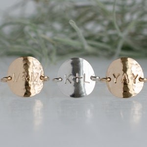 May include: Three hammered metal rings with personalized engravings. The rings are gold and silver with the engravings "M&M", "K+L", and "YAY".
