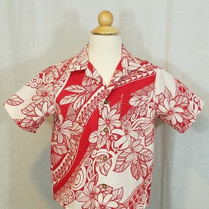 Puede incluir: Una camisa blanca de manga corta con un estampado floral rojo y blanco. El estampado presenta flores y hojas estilizadas con diseños geométricos.