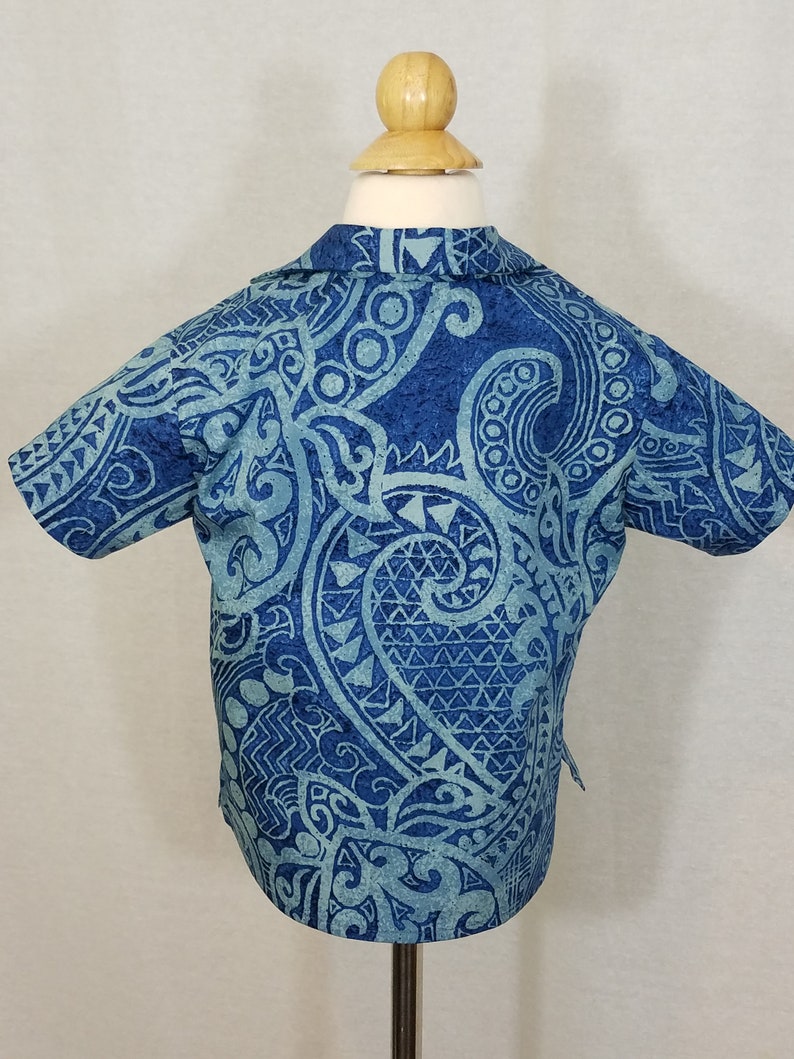 Puede incluir: Una camisa de manga corta azul y azul claro con estampado y cuello.