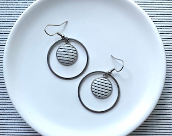 Dangle earrings featuring a 3cm hoop and 14mm black and white stripe leather bezel. Surgical stainless steel. All hypoallergenic.