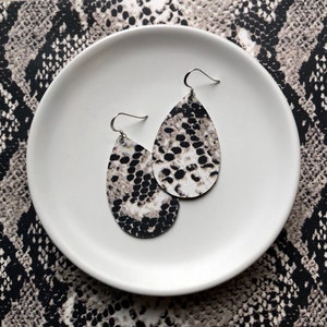 May include: A pair of teardrop-shaped earrings with a black and white snake skin pattern.