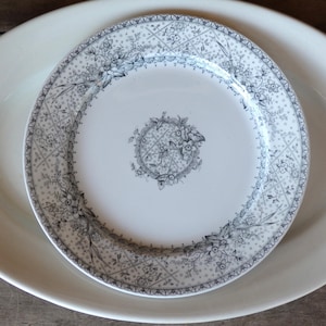 May include: A white oval serving platter with a white and gray floral patterned plate on top. The plate has a detailed floral design around the rim and center. The design is in shades of gray.