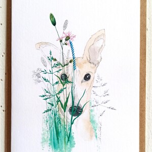 Könnte beinhalten: Ein Aquarellbild eines Hundefaces, das hinter einem Büschel grüner und blauer Wildblumen hervorlugt. Der Hund hat ein hellbraunes Fell und große, dunkle Augen.