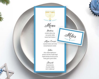 May include: A blue and white place setting with a menu card featuring a gold menorah and the text "Menu, Masters, Main Course, Sides, Dessert". The menu lists a variety of dishes, including smoked salmon dip, roasted chicken with herbs, and hamantaschen. A blue place card with the name "Miles" is also visible.