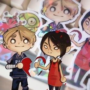 May include: A collection of cartoon-style stickers featuring characters and symbols. The stickers include figures in various outfits, broken hearts, and zombie-like faces. The color palette includes red, blue, and green, with a holographic effect.