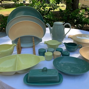 May include: A set of vintage mid-century modern dinnerware in shades of green and yellow. The set includes a teapot, serving bowls, a butter dish, and a divided serving dish.