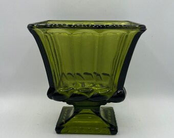 May include: A square green glass vase with a fluted design and a twisted base.