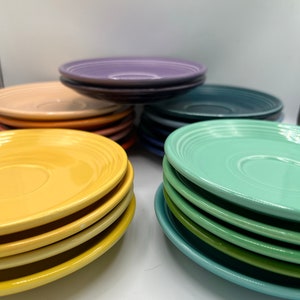 May include: A stack of yellow, green, and blue ceramic saucers. The saucers are stacked in a pyramid shape.