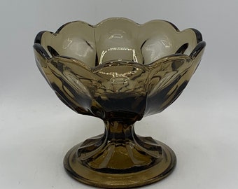 May include: A brown glass pedestal bowl with a scalloped rim and a fluted base.