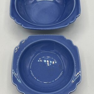May include: Two blue ceramic bowls with square rims and a slightly rounded bottom. The bowls are a deep blue color and have a glossy finish.