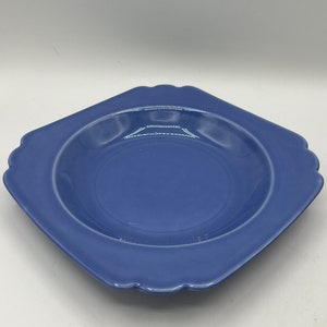 May include: A square, light blue ceramic bowl with a scalloped edge. The bowl is empty and has a glossy finish.