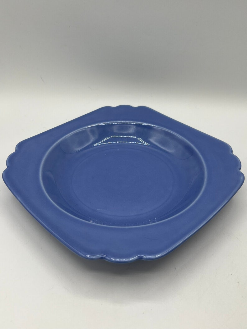 May include: A square, light blue ceramic bowl with a scalloped edge. The bowl is empty and has a glossy finish.