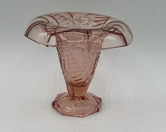 May include: A pink glass vase with a flared top and a textured, patterned design. The vase has a hexagonal base and a conical stem. The top has a ruffled edge. The vase is likely vintage and is suitable for displaying flowers.