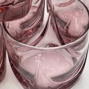May include: Set of six clear glass tumblers with a swirling design. The glasses have a light purple hue.