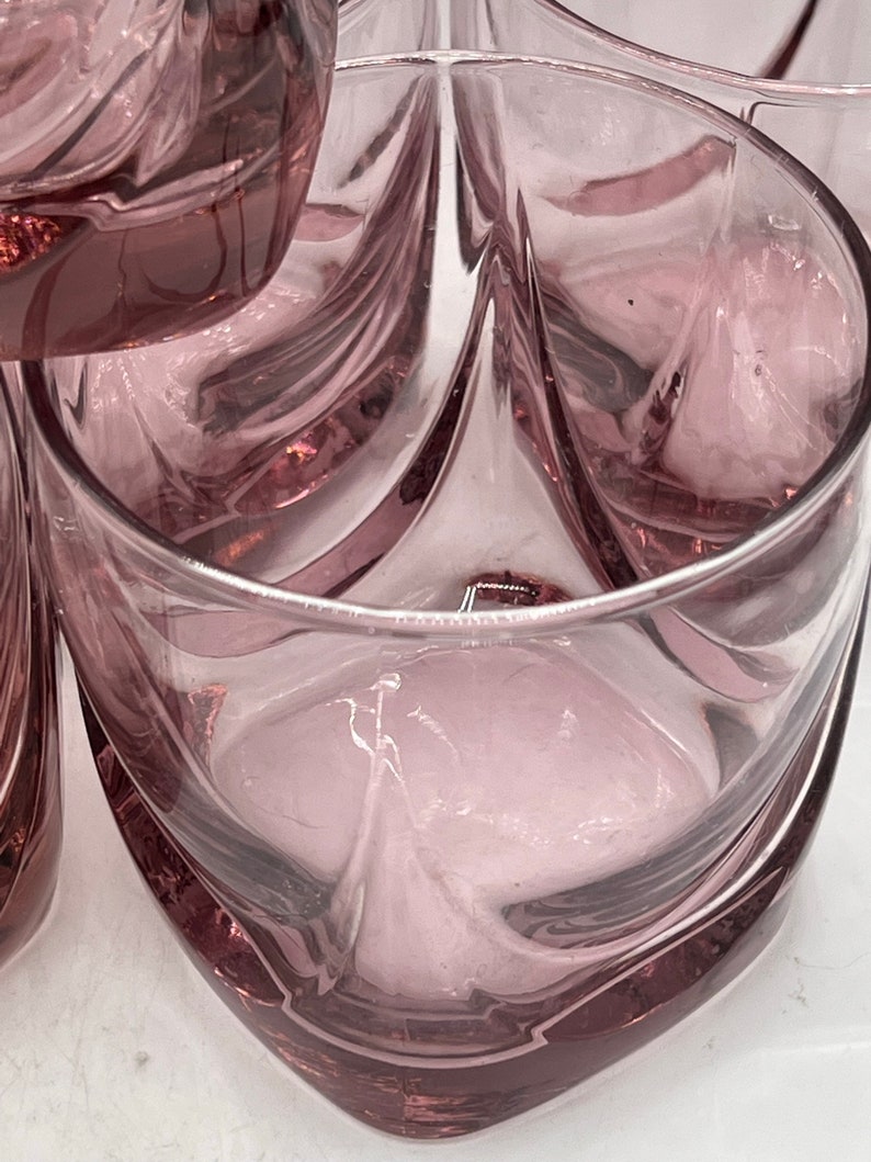 May include: Set of six clear glass tumblers with a swirling design. The glasses have a light purple hue.