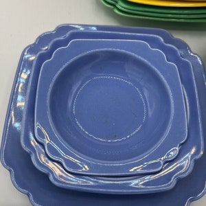 May include: A set of three blue ceramic plates with scalloped edges. The plates are stacked on top of each other, with the largest plate on the bottom and the smallest plate on top.