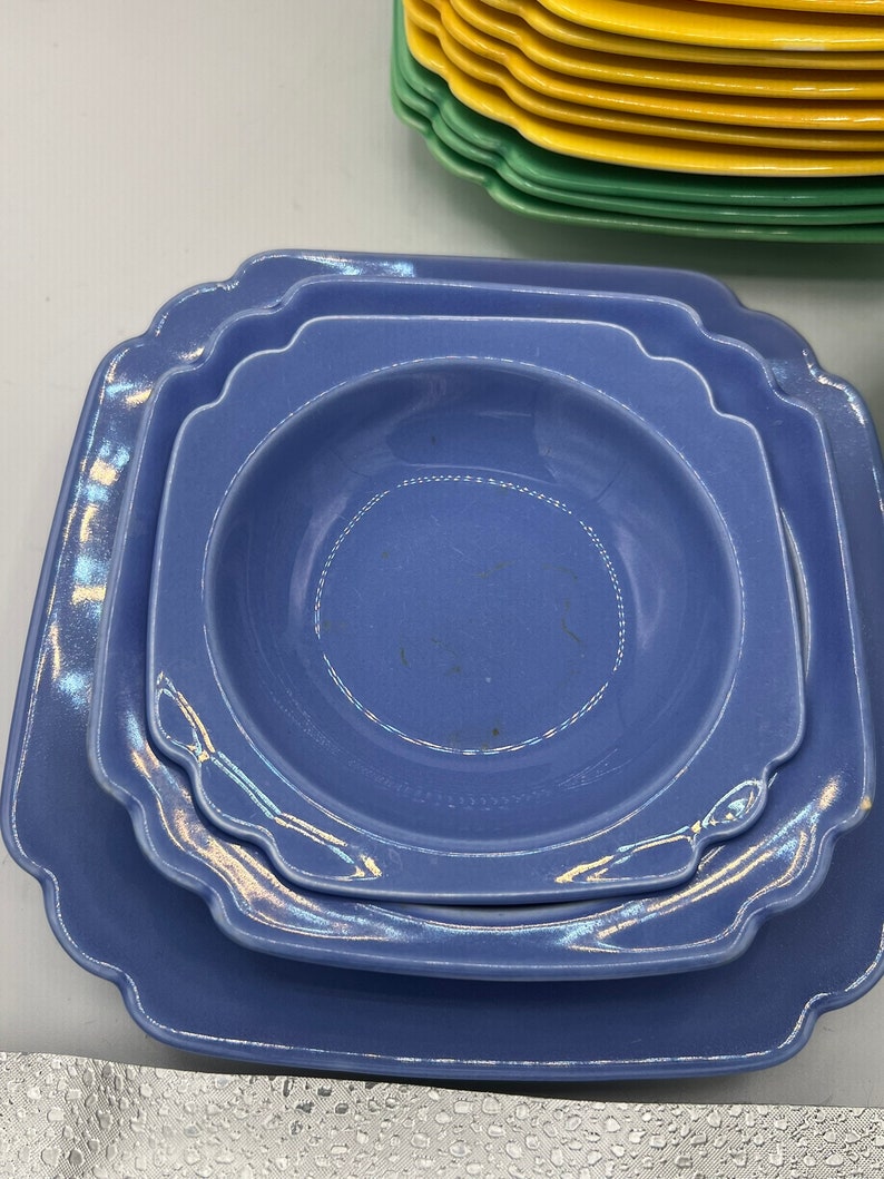 May include: A set of three blue ceramic plates with scalloped edges. The plates are stacked on top of each other, with the largest plate on the bottom and the smallest plate on top.