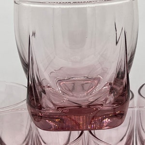 May include: Set of six clear glass tumblers with a pink hue and a unique, faceted design. The glasses are stacked on top of each other.