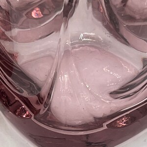 May include: A clear glass tumbler with a square base and a textured, rippled design. The glass has a light purple hue.