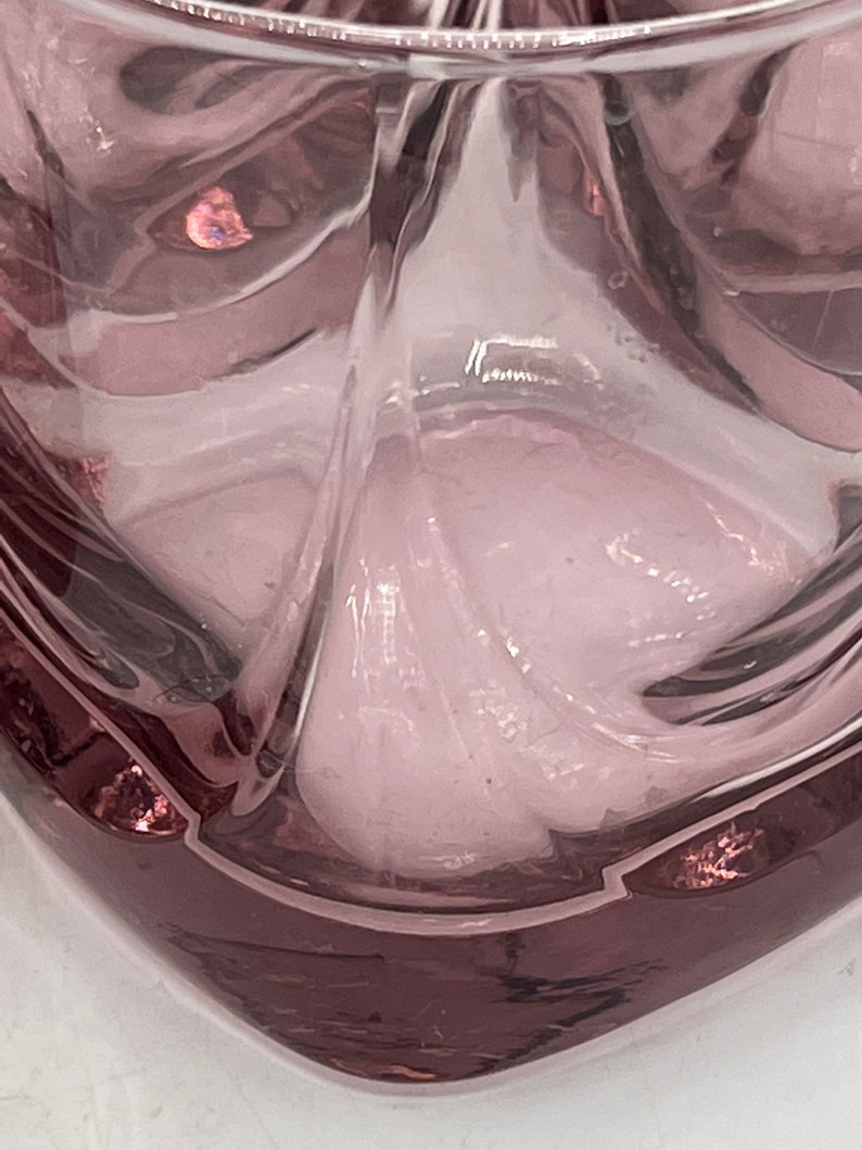 May include: A clear glass tumbler with a square base and a textured, rippled design. The glass has a light purple hue.