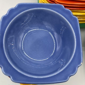 May include: A blue ceramic bowl with a scalloped edge. The bowl is empty and has a white rim.