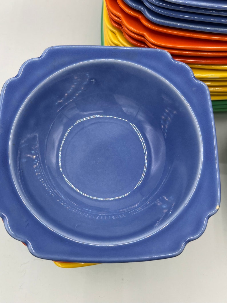 May include: A blue ceramic bowl with a scalloped edge. The bowl is empty and has a white rim.