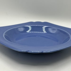 May include: A light blue ceramic bowl with a scalloped edge. The bowl is empty and has a slight sheen.