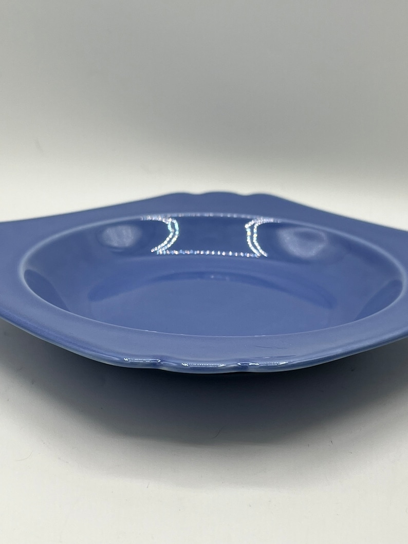 May include: A light blue ceramic bowl with a scalloped edge. The bowl is empty and has a slight sheen.