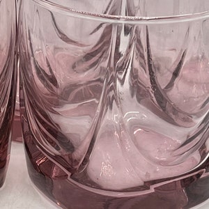 May include: Set of four clear glass tumblers with a swirling, textured design. The glasses have a light pink hue and a square base.