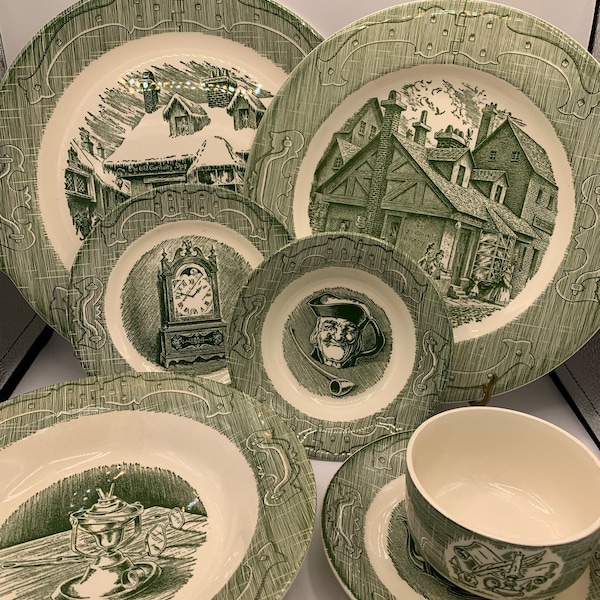 May include: A collection of white ceramic dinnerware featuring green transferware patterns. The set includes plates, bowls, and a cup, each decorated with detailed black and white illustrations of historical scenes, a clock, and a pipe.