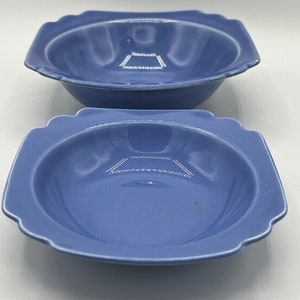 May include: Two blue ceramic bowls with a square shape and scalloped edges. The bowls are slightly different sizes.