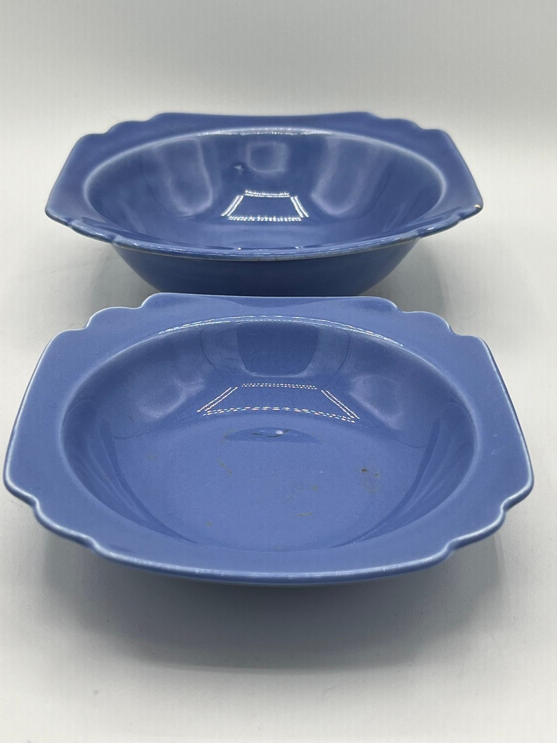 May include: Two blue ceramic bowls with a square shape and scalloped edges. The bowls are slightly different sizes.