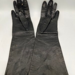 Könnte beinhalten: Ein Paar lange schwarze Lederhandschuhe.
