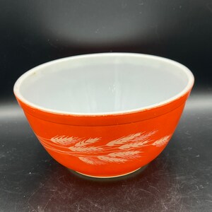 May include: Orange mixing bowl with a white wheat design.