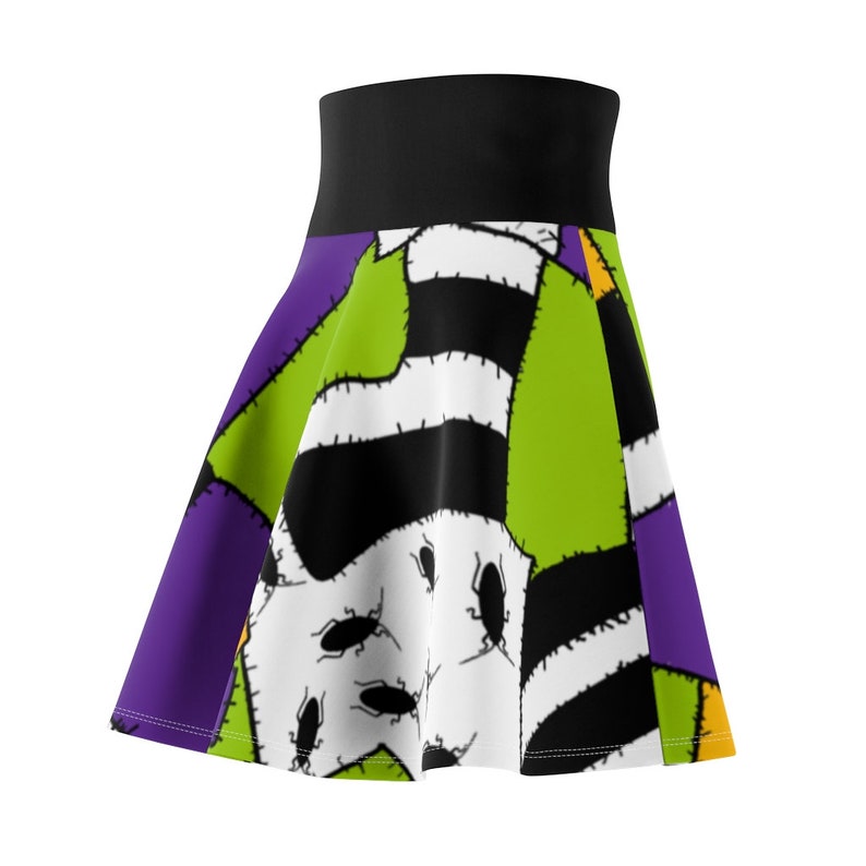May include: A green, black, white, and purple skirt with a patchwork design featuring a stitched-up creature with bugs. The skirt has a black waistband.