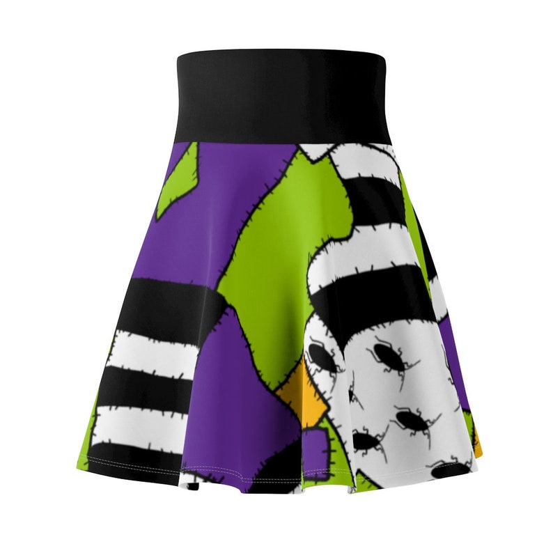 May include: A purple, green, black, and white skirt with a patchwork design featuring a stitched-together creature with a striped hat.