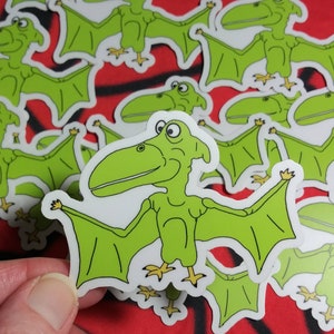 May include: A set of green and white stickers featuring a cartoon pterodactyl with a long beak and wings. The stickers are perfect for adding a whimsical touch to any surface.