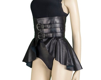May include: A black ribbed sleeveless top paired with a black leather-look corset belt featuring two horizontal straps with silver-toned metal buckles and a flared peplum hem, worn over a black bodysuit on a mannequin display.