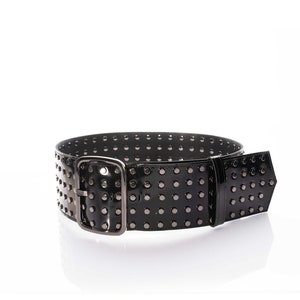 May include: A wide black belt with a glossy finish, featuring multiple rows of small, dark metallic studs across the entire length. The belt includes a large, rectangular, dark metallic buckle and a matching belt loop, creating a uniform look.