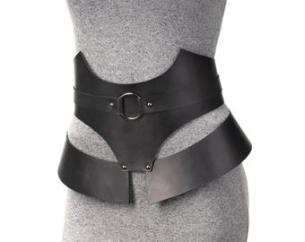May include: A wide black waist belt featuring a structured design with a central silver-toned metal ring. The belt consists of two distinct horizontal bands connected by vertical segments, secured with small silver-toned rivets across the front.