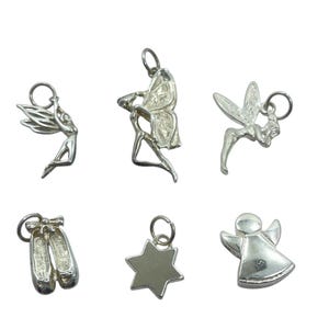 May include: Six silver charms in various shapes, including fairies, ballet slippers, a star, and an angel. Each charm has a small loop for attaching to a necklace or bracelet. The charms are displayed against a white background.