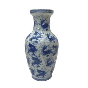 Könnte beinhalten: Eine hohe Keramikvase mit weißem Grund und blauem Blumenmuster. Die Vase hat einen breiten Körper, der sich nach oben und unten verjüngt. Das blaue Muster zeigt stilisierte Fische und florale Elemente. Der Rand und der Sockel haben einen detaillierten blauen Rand.