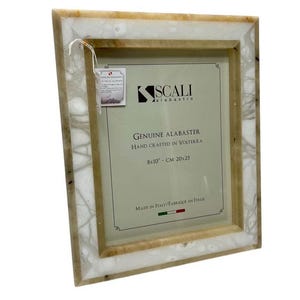 May include: A rectangular alabaster picture frame with a cream and white marbled design. The frame is labeled "SCALI alabastro" and "GENUINE ALABASTER HAND CRAFTED IN VOLTERRA 8x10" (20x25 cm). Made in Italy.