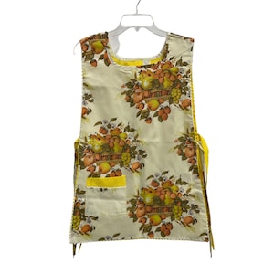 May include: A vintage yellow and white apron with a fruit print. The apron has a large pocket on the front and ties at the neck and waist.