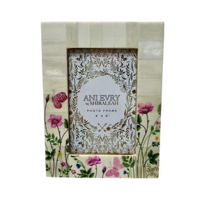 Op de afbeelding: Witte fotolijst van bot met een bloemenmotief en vlinders. De lijst is 10,16 cm bij 15,24 cm en heeft de tekst "Ani Every by Shiraleeah Photo Frame 4" x 6" aan de voorkant.