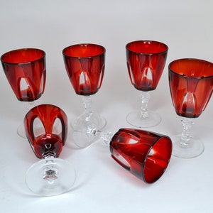 Pode incluir: Conjunto de seis copos de vinho tinto com hastes e bases transparentes. Os copos têm um design facetado e são feitos de vidro.