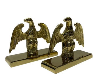 May include: A pair of gold-toned brass eagle bookends. Each eagle is perched on a rectangular base.
